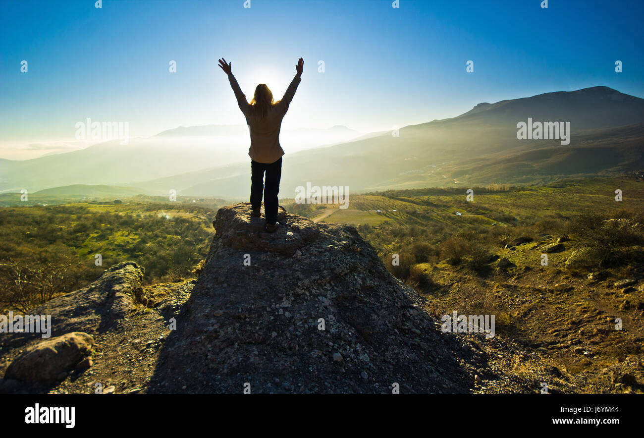 girl with hands up in the mountsins against sun  Stock Photo