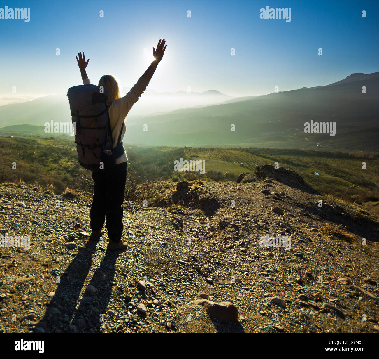girl with hands up in the mountains against sun  Stock Photo