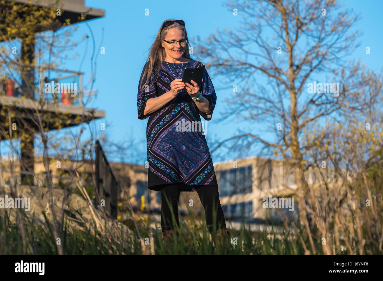 Woman standing in garden text messaging Stock Photo