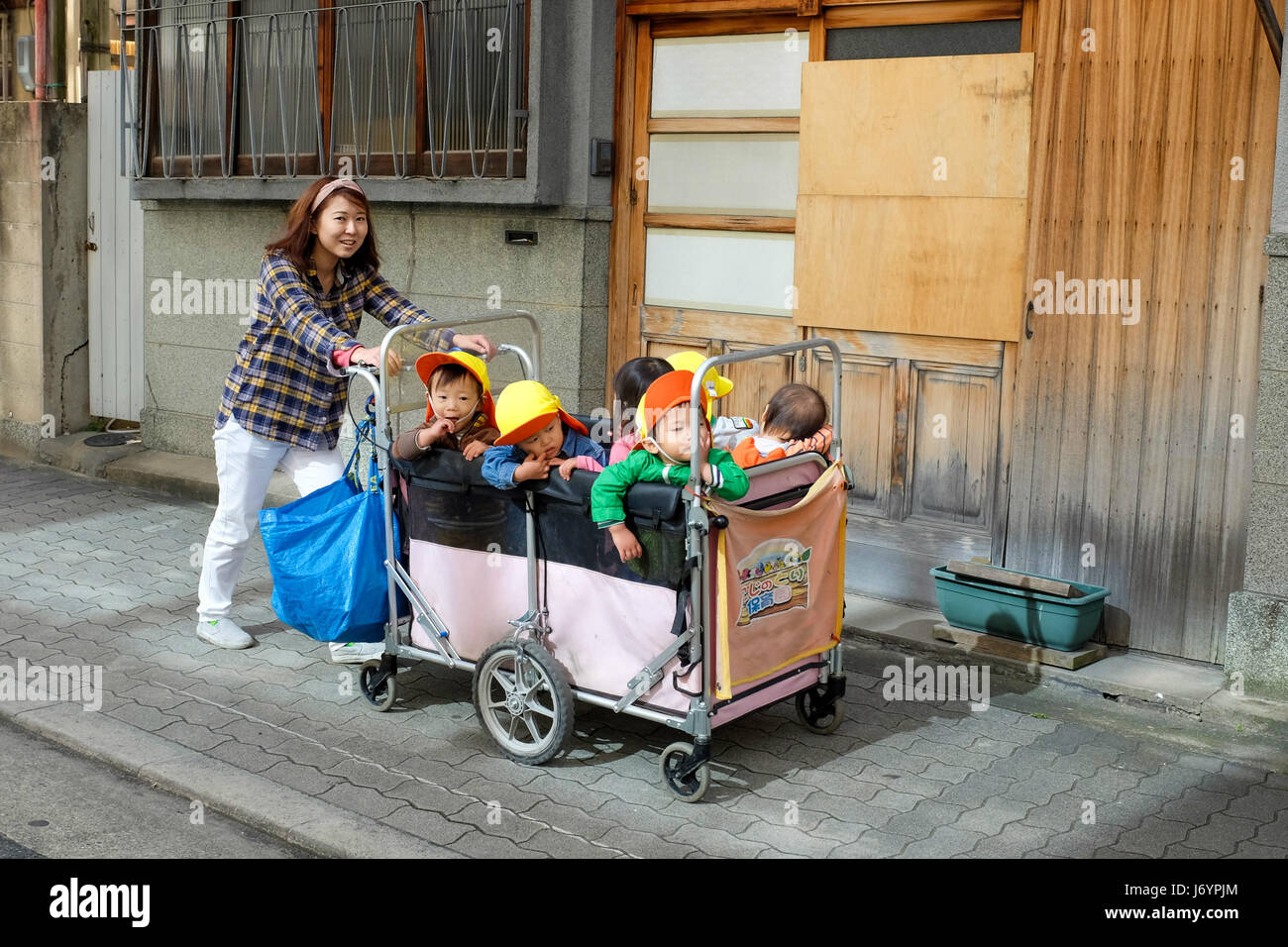 A teacher pushing a cart full of children. Stock Photo