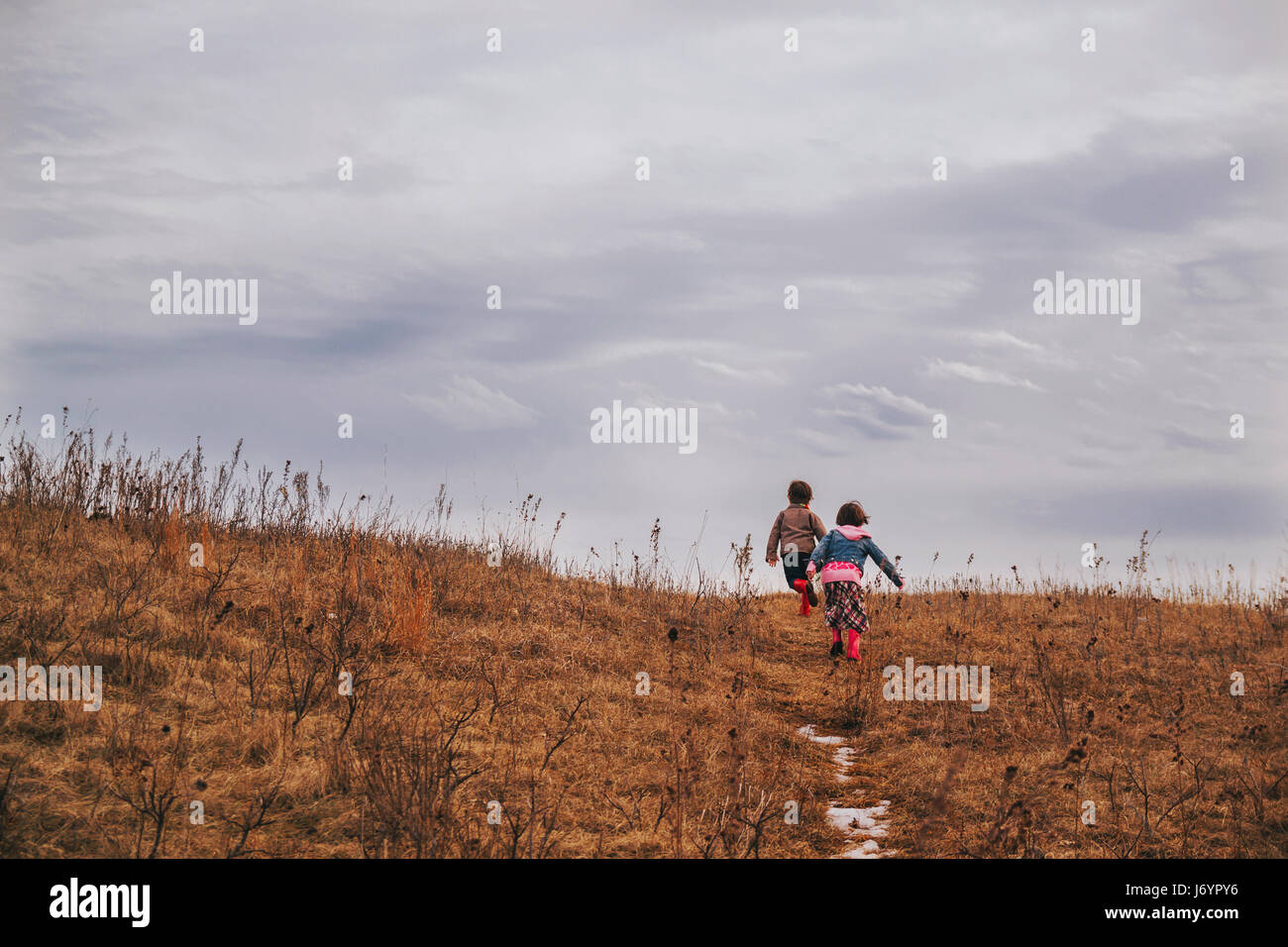 Two children running up a hill Stock Photo