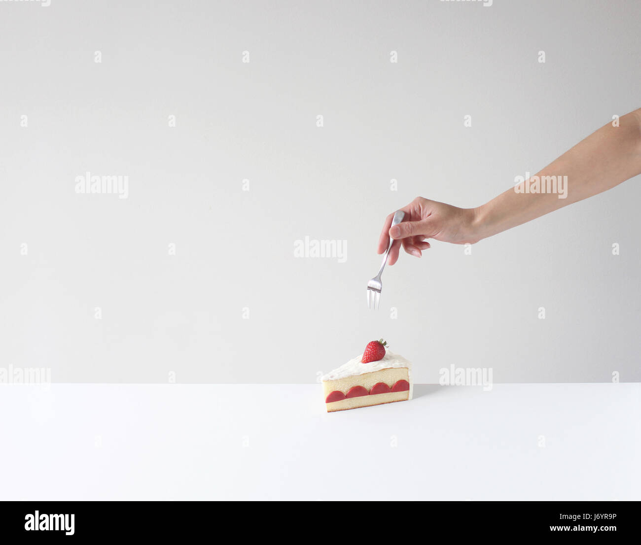 Hand holding a fork about to eat a slice of cake Stock Photo