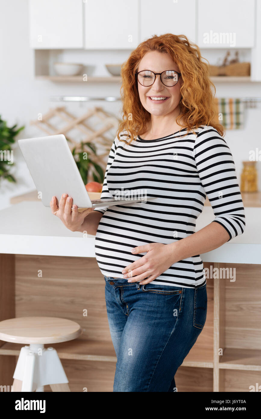 Radiant expectant mother working on laptop Stock Photo