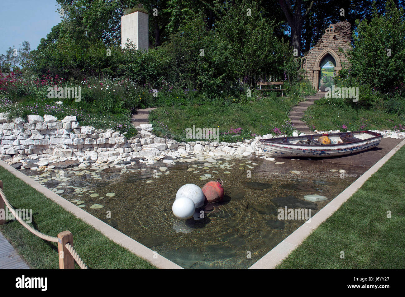 A fishing boat in the Welcome to Yorkshire Garden during the press preview of the RHS Chelsea Flower Show at the Royal Hospital Chelsea, London. The garden, inspired by the scenery of the Yorkshire coastline, features cliffs, a beach and a ruined abbey. Stock Photo