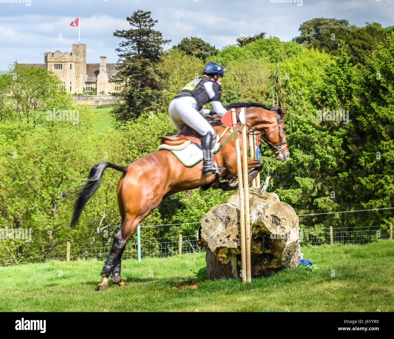 Pippa Funnell on her horse MGH Grafton Street clears a tree trunk obstacle with Rockingham castle in the background on a sunny day during the cross co Stock Photo