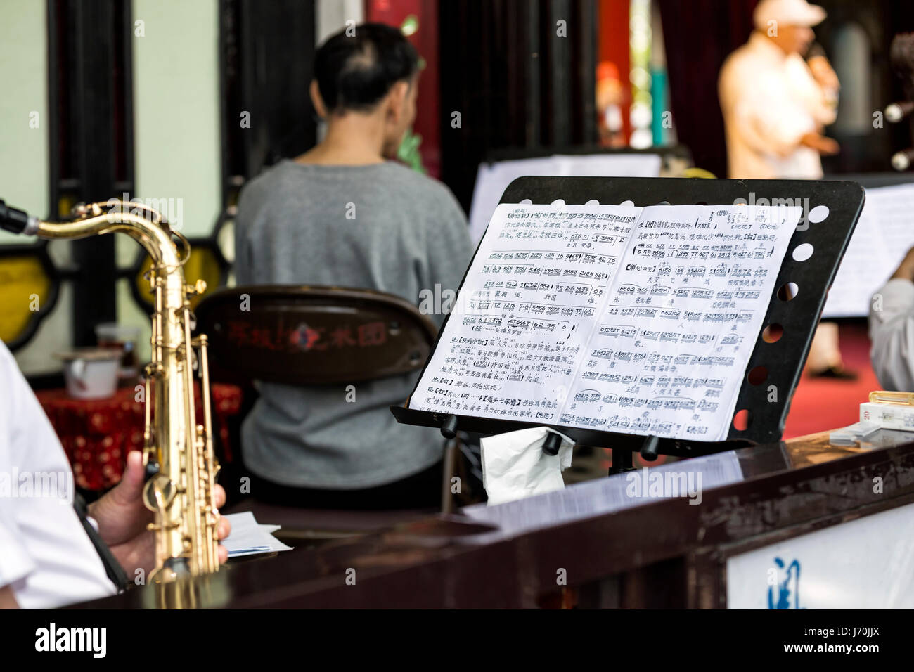 April 2017 - Guangzhou, China. Chinese Opera musician playing a tenor saxophone while reading Chinese music sheet. Stock Photo