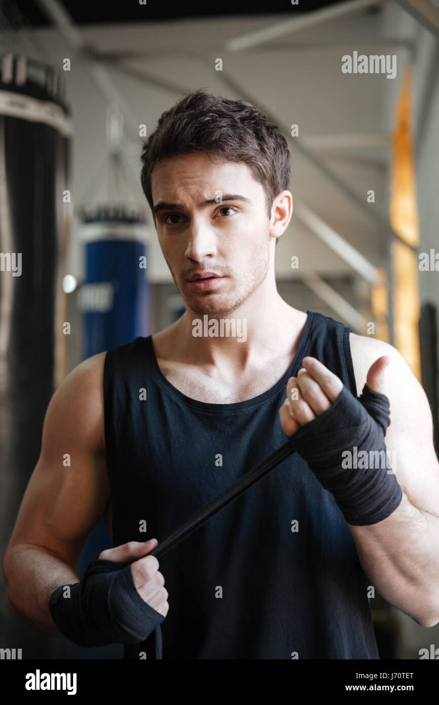 Strong serious sportsman looking away agressively while training in gym Stock Photo