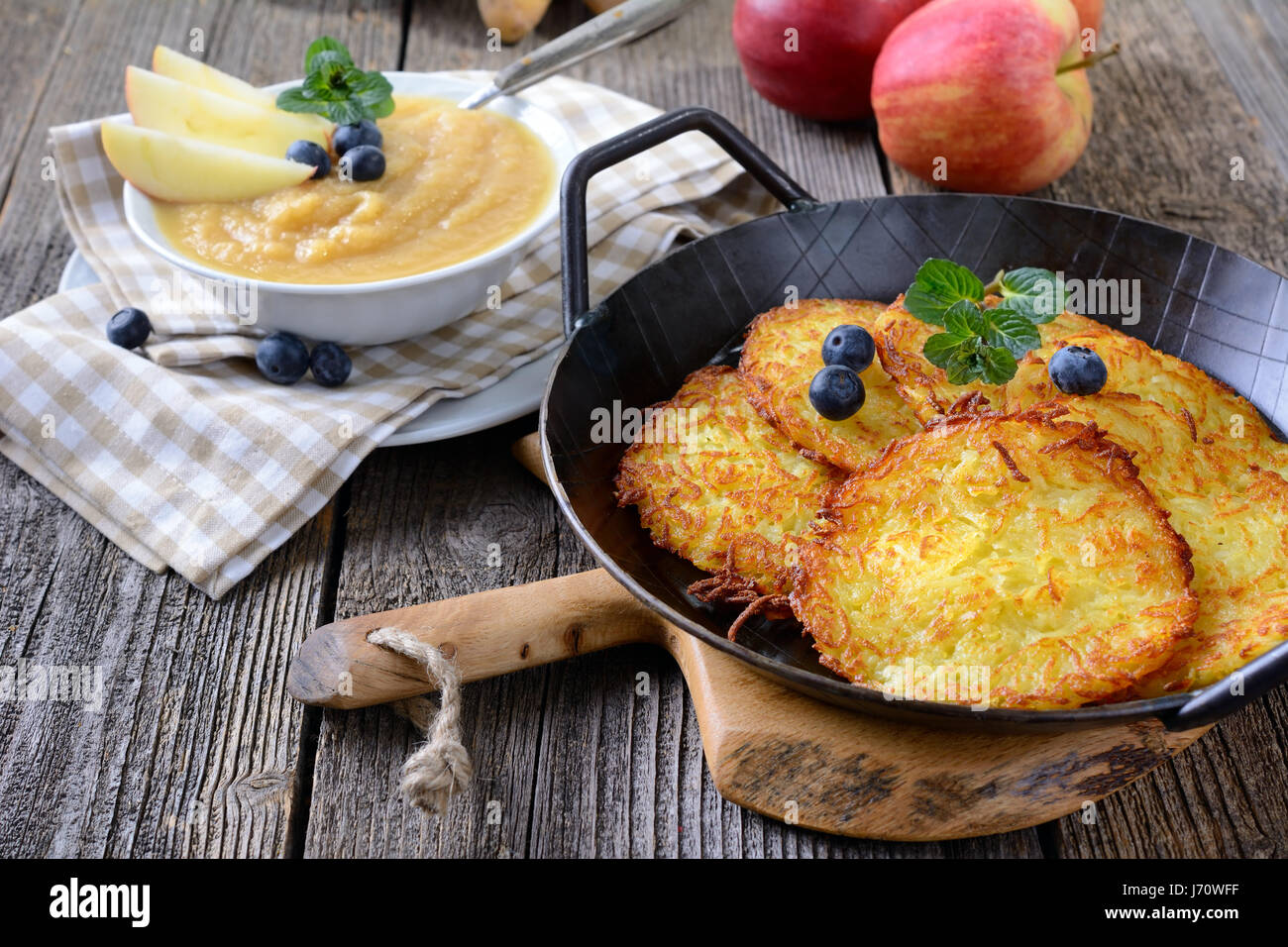 Homemade crispy fried potato pancakes served in an iron frying pan with apple sauce Stock Photo