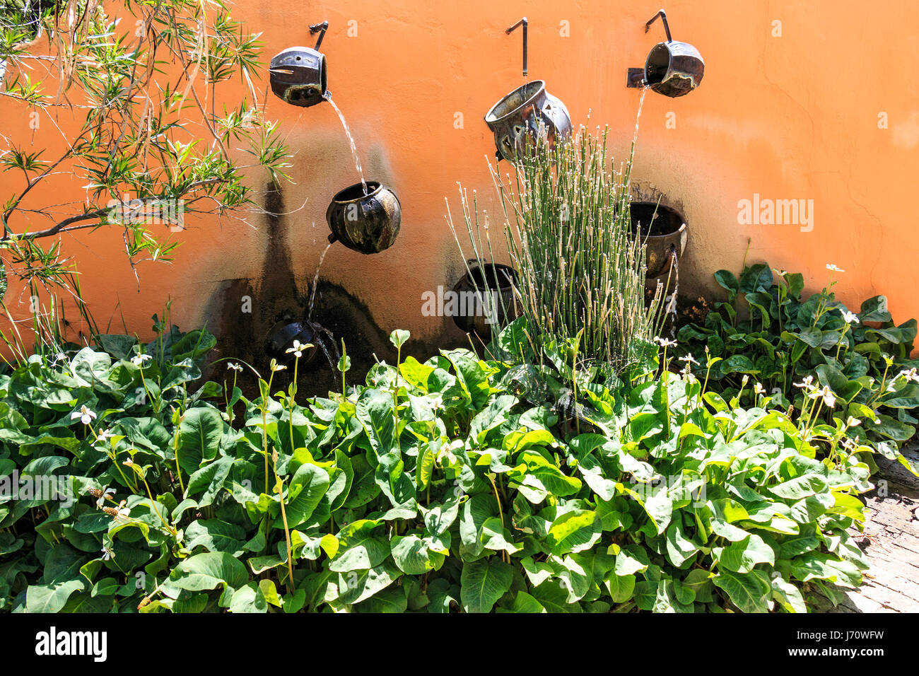 Water pours from pot to pot along a wall at Tohono Chul park, a beautiful botanical garden in Tucson, Arizona. Stock Photo