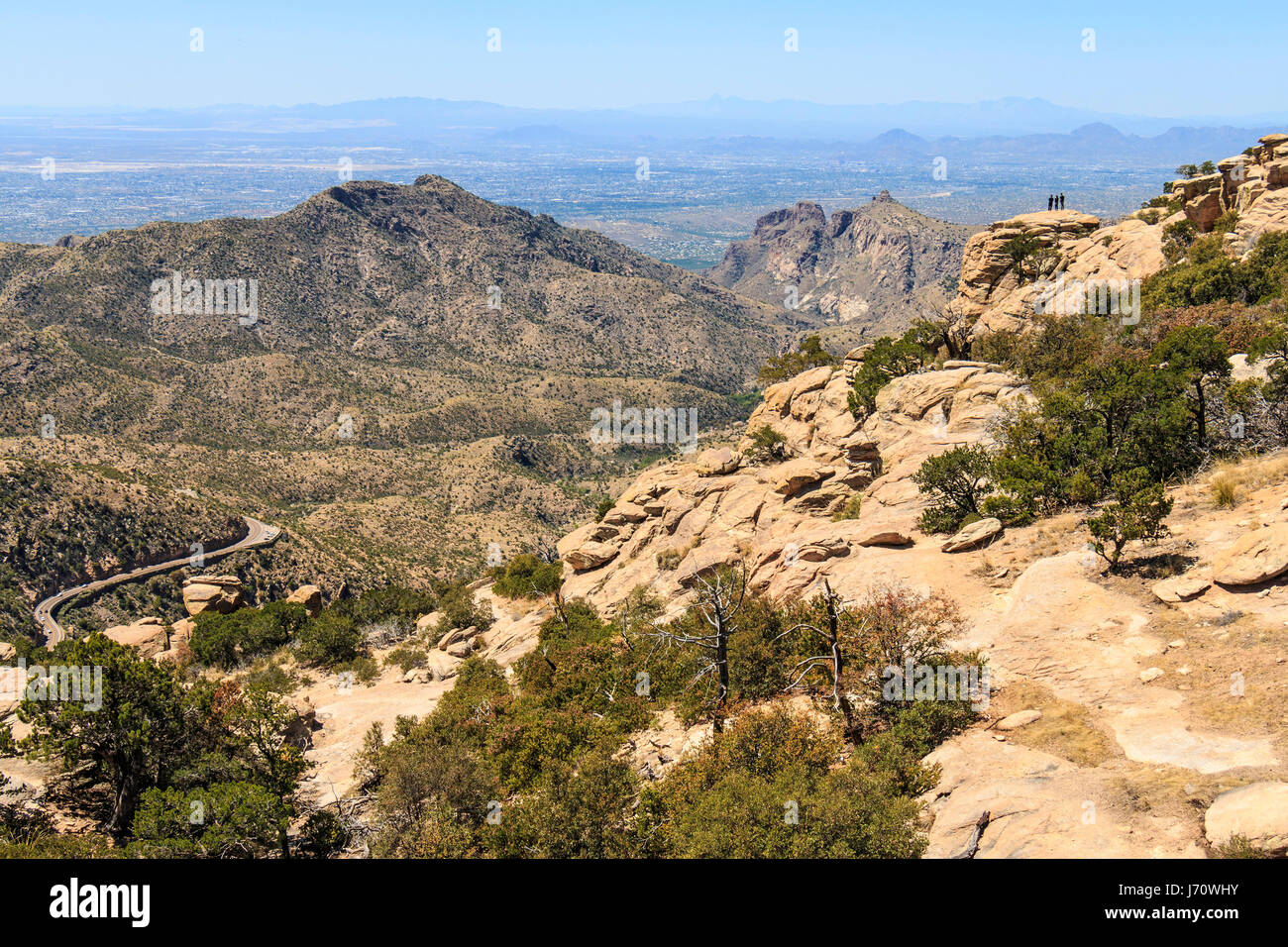 Three people admire the view from a rock at Windy Point, along the road up Mount Lemmon. With a summit elevation of 9,159 feet (2,792 m), it is the hi Stock Photo