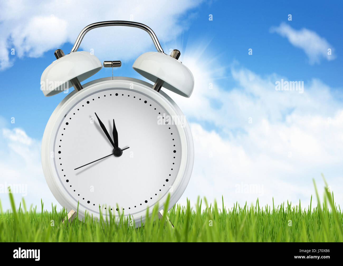 Blank alarm clock on grass with sky Stock Photo