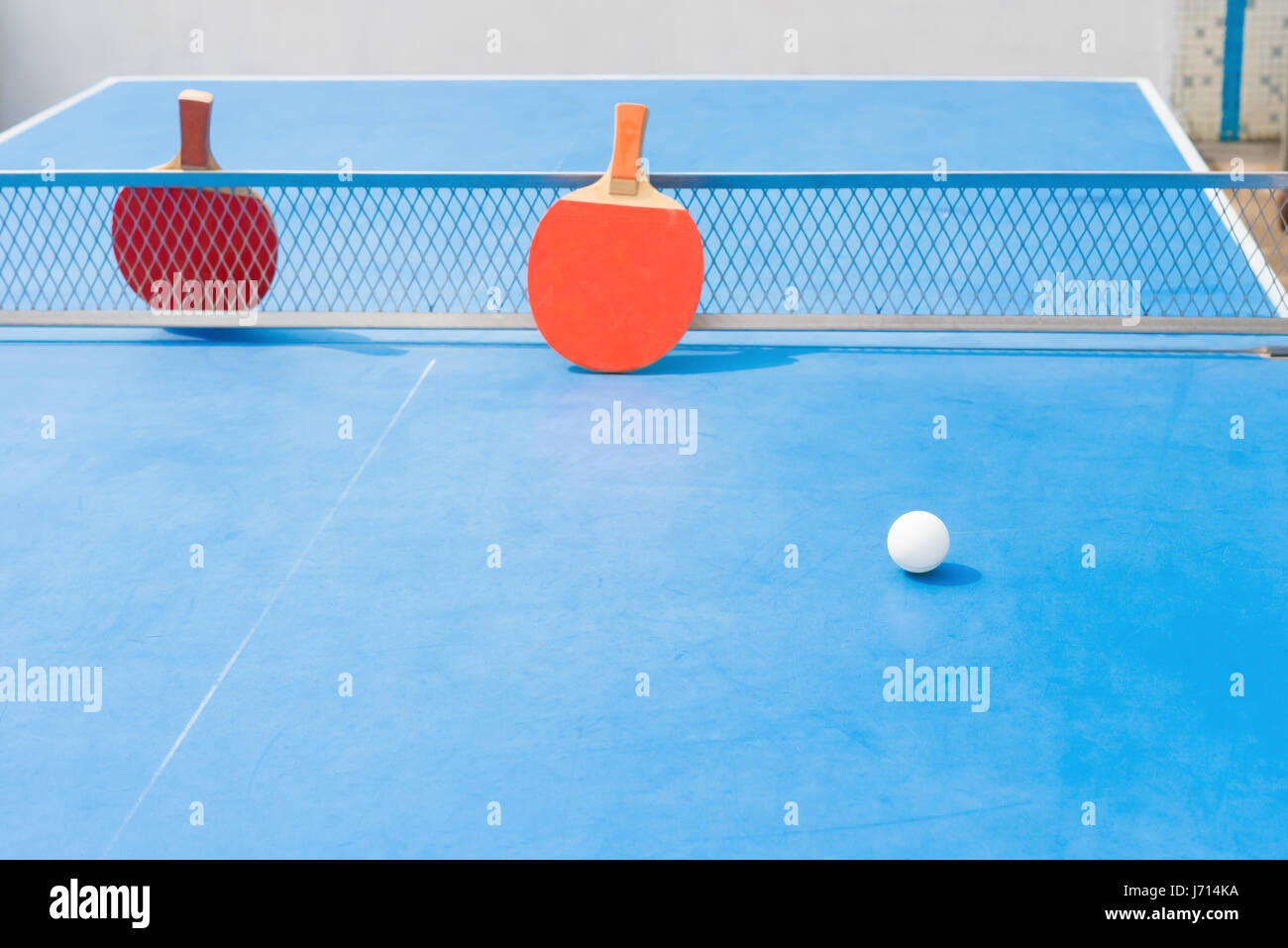 pingpong rackets and ball and net on a blue pingpong table Stock Photo