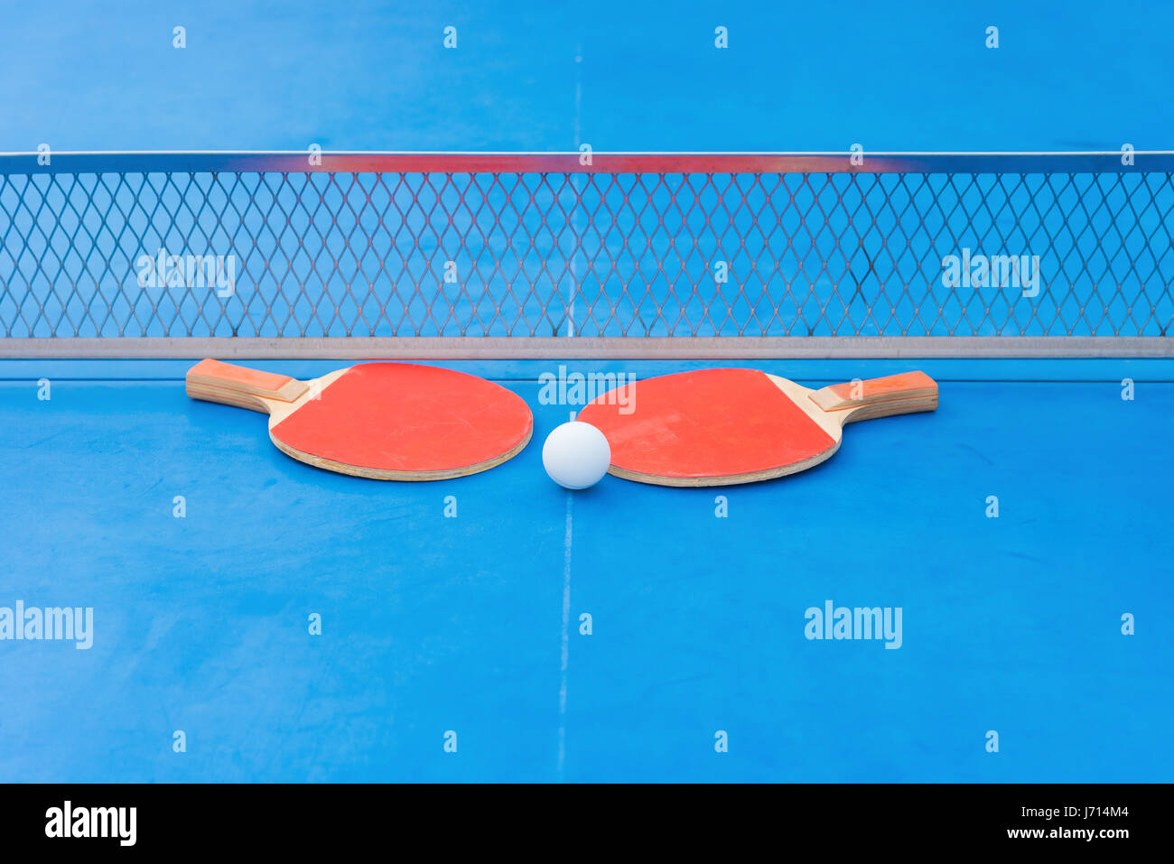 pingpong rackets and ball and net on a blue pingpong table Stock Photo