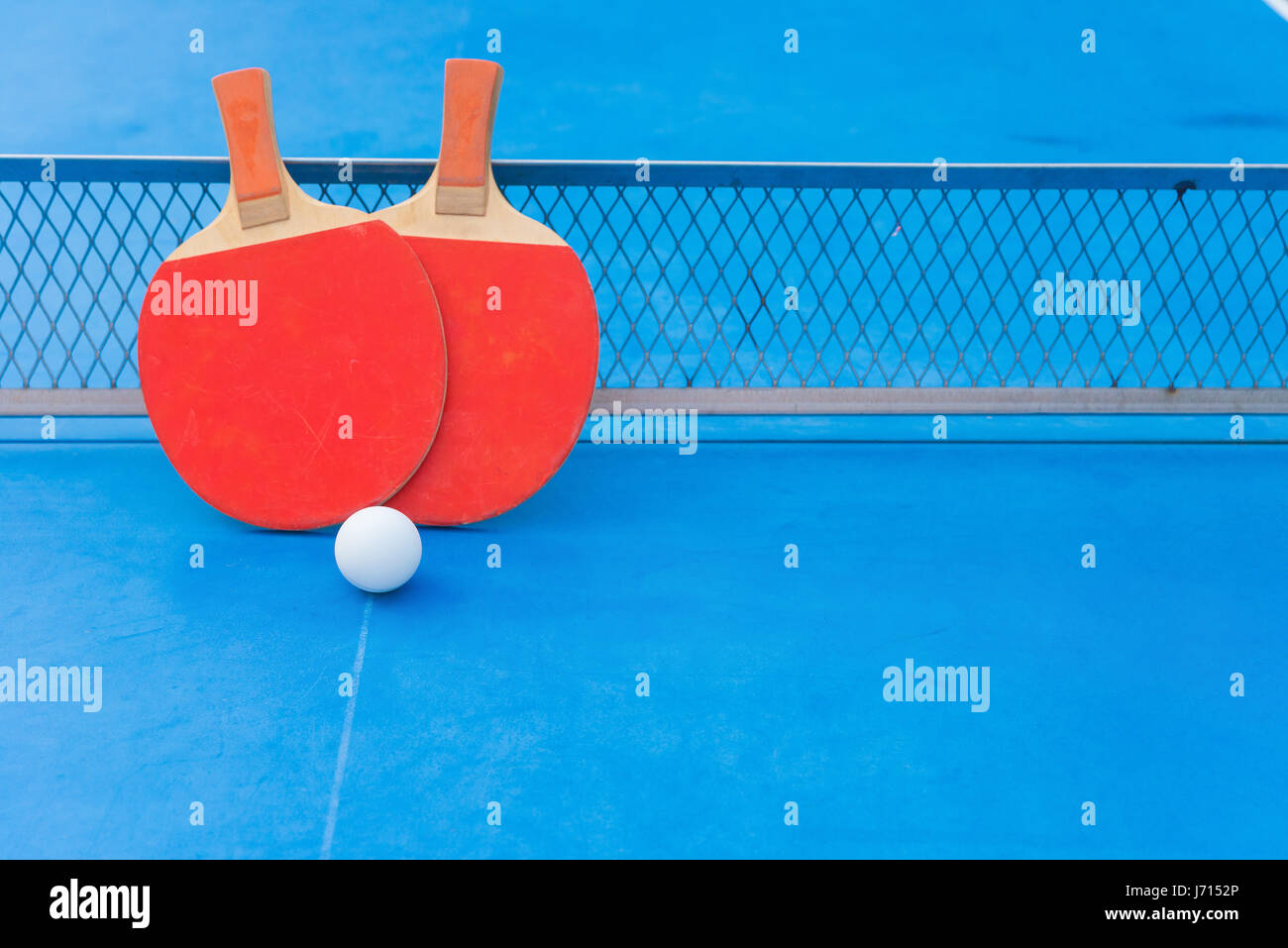 two pingpong rackets and ball and net on a blue pingpong table with copy space Stock Photo