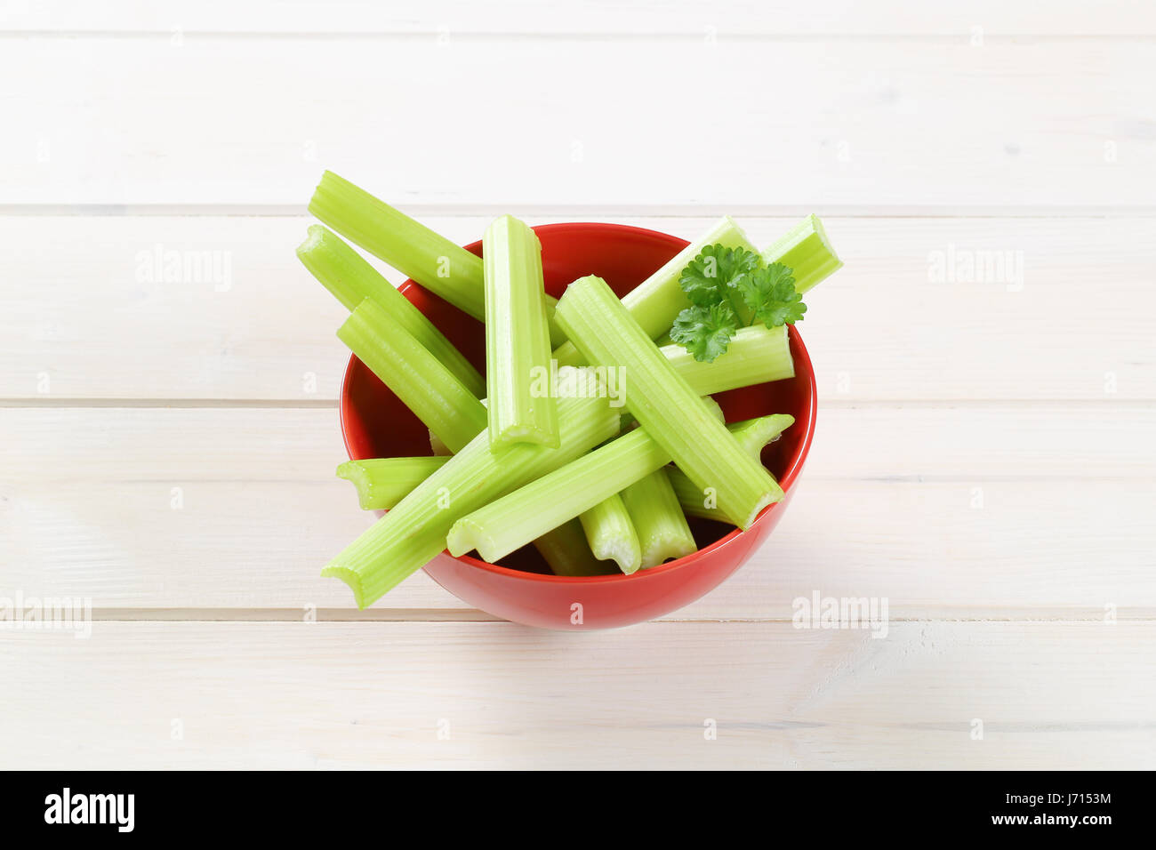 bowl of green celery stems on white wooden background Stock Photo