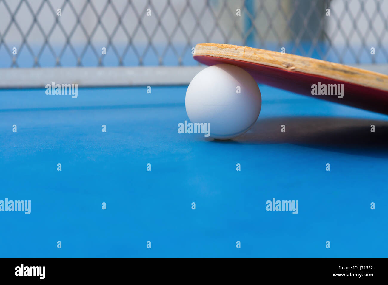 pingpong rackets and ball and net on a blue pingpong table close up Stock Photo