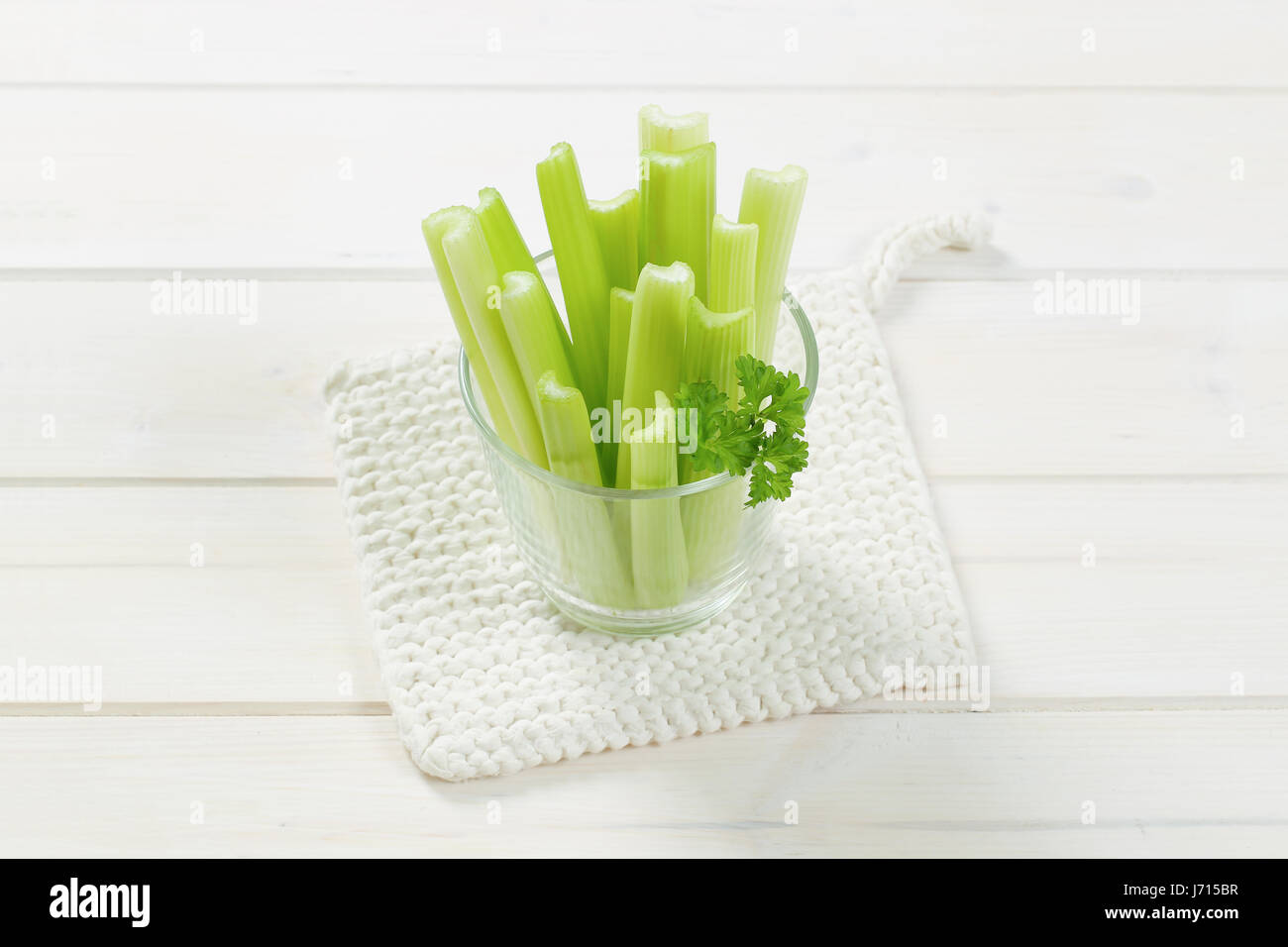 glass of green celery stems on white table mat Stock Photo