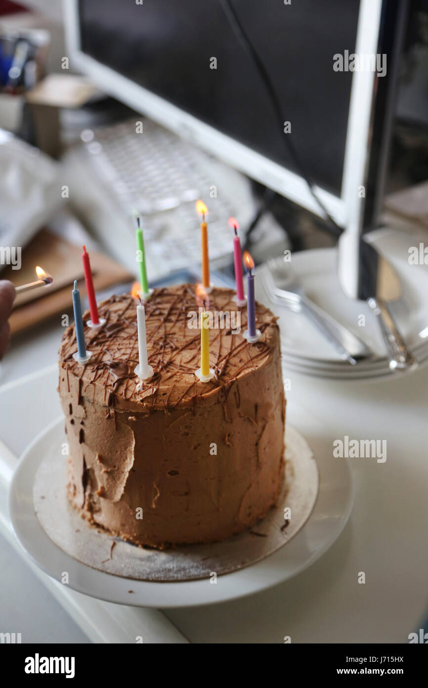 Lighting candles on chocolate birthday cake in office Stock Photo - Alamy