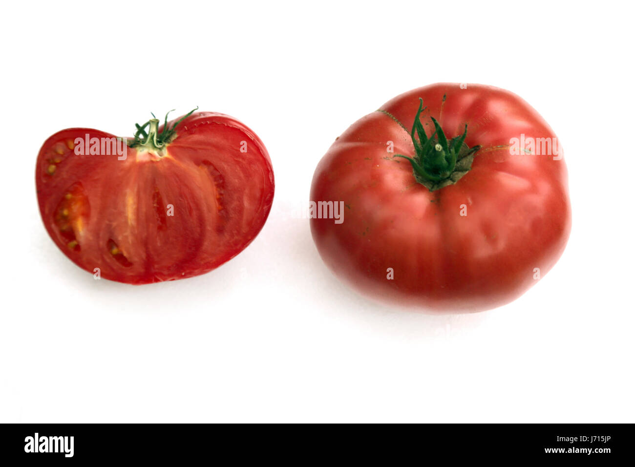 One half of a large tomato and a whole tomato Stock Photo