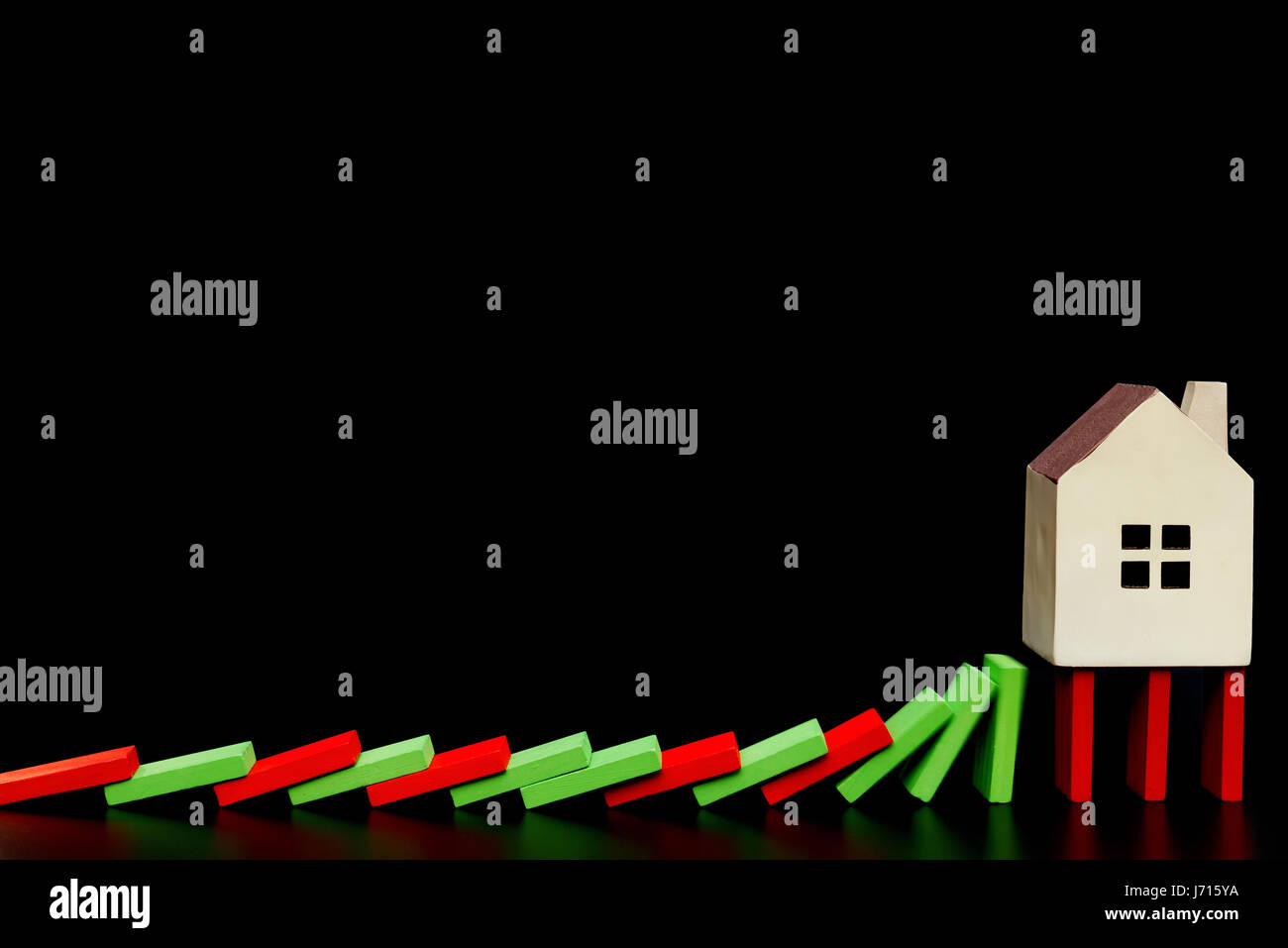 house standing on falling dominos on black background as a financial concept Stock Photo