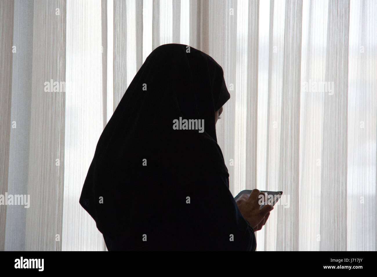 Woman in hijab playing with iPad in a restaurant, Yazd, Iran Stock Photo