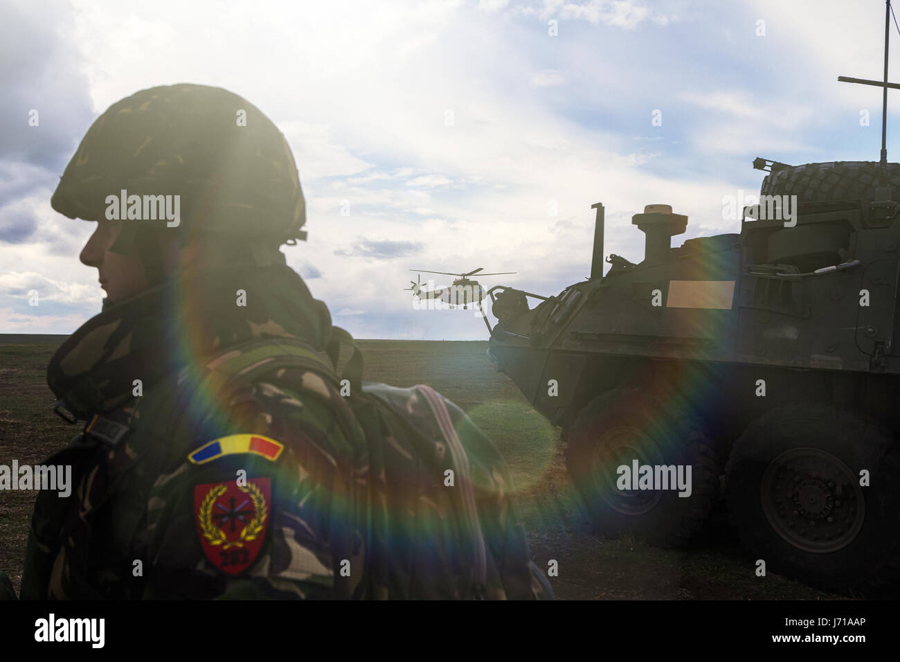 Soldiers run for a new position while being defended by a Romanian tanks and an attack helicopter during the NATO military drill 'Wind Spring -15' at Smardan shooting range. Stock Photo
