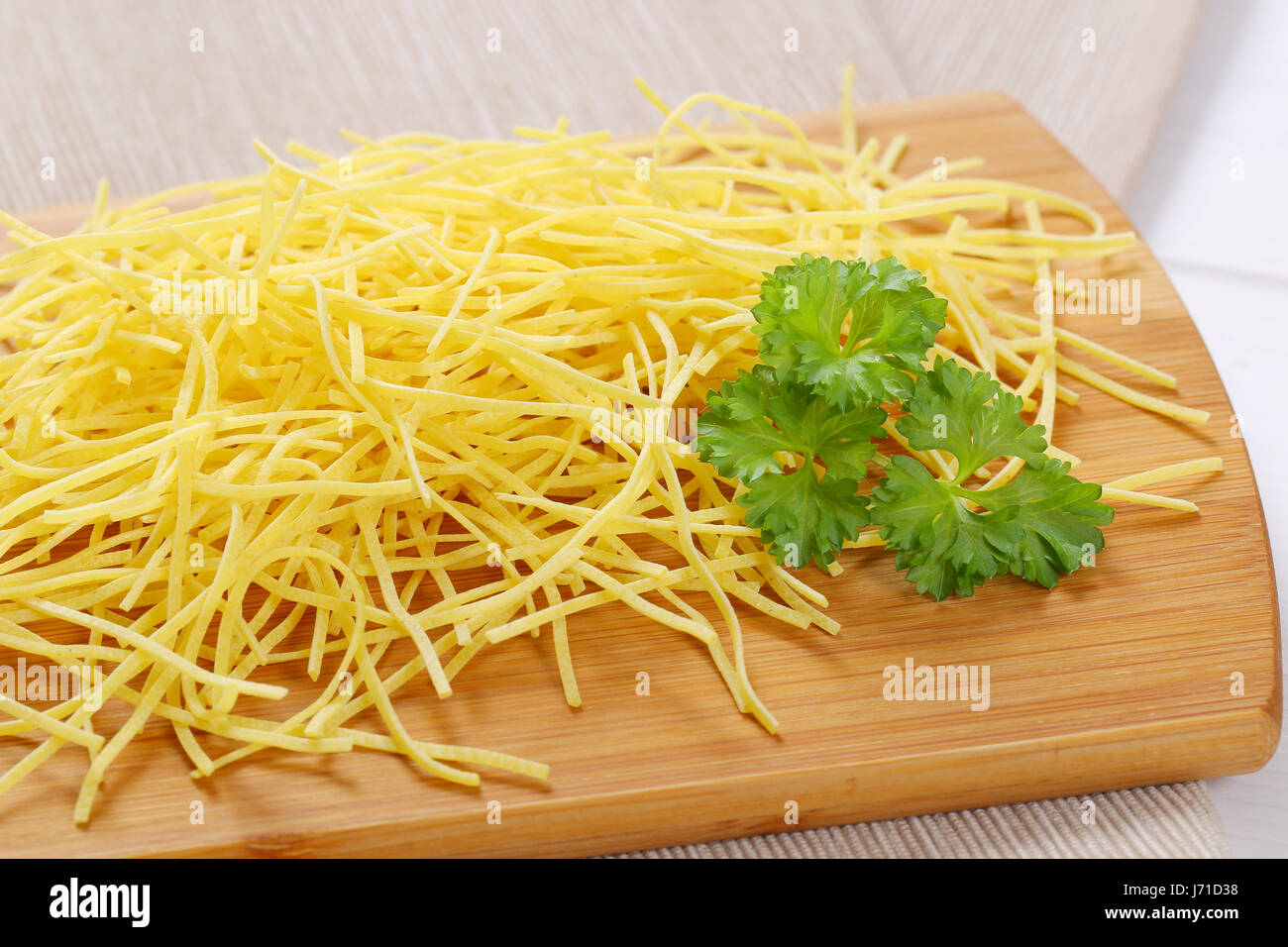 heap of dry soup noodles on wooden cutting board - close up Stock Photo