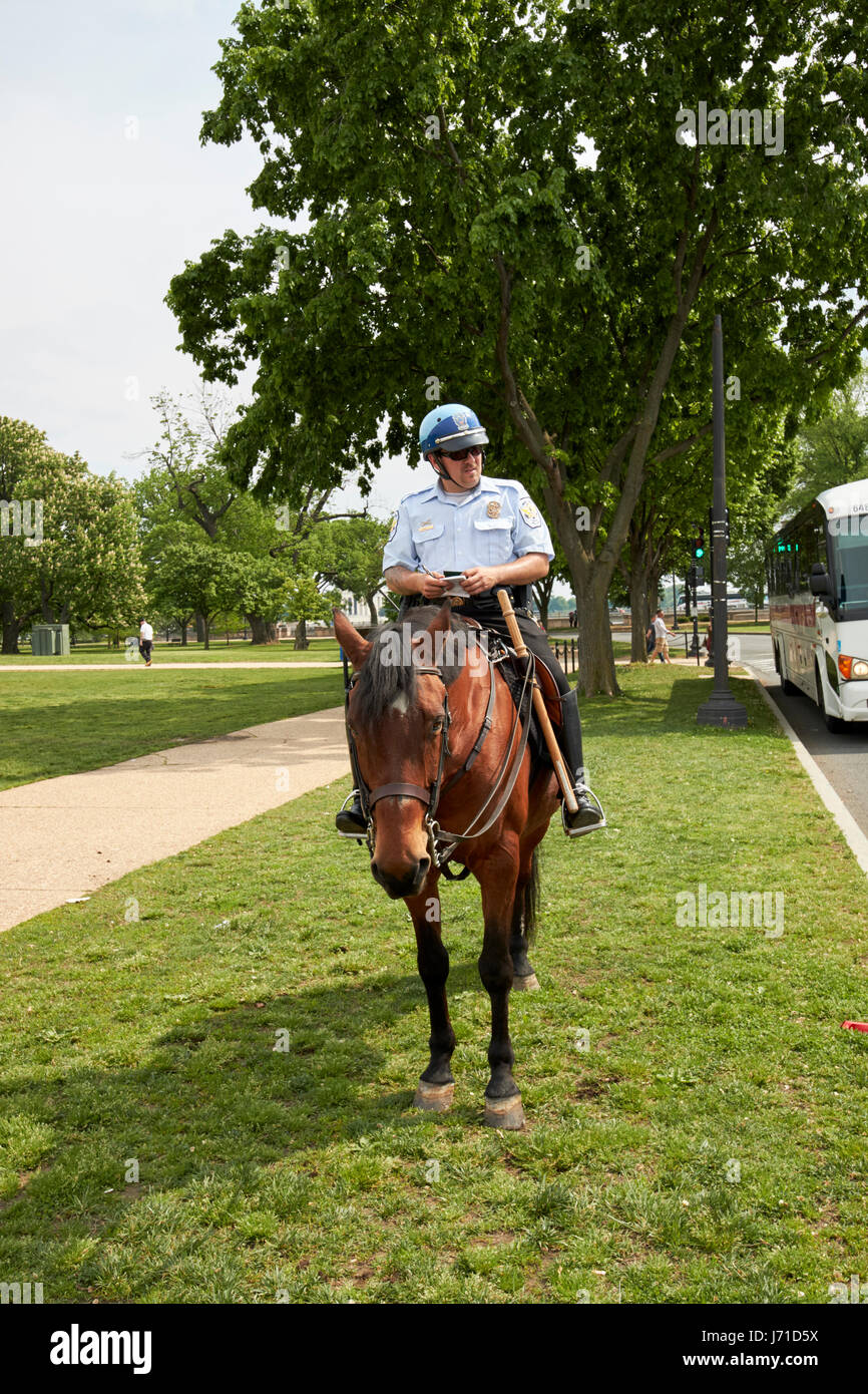 US park police on horseback writing a ticket for a parked coach on the national mall Washington DC USA Stock Photo