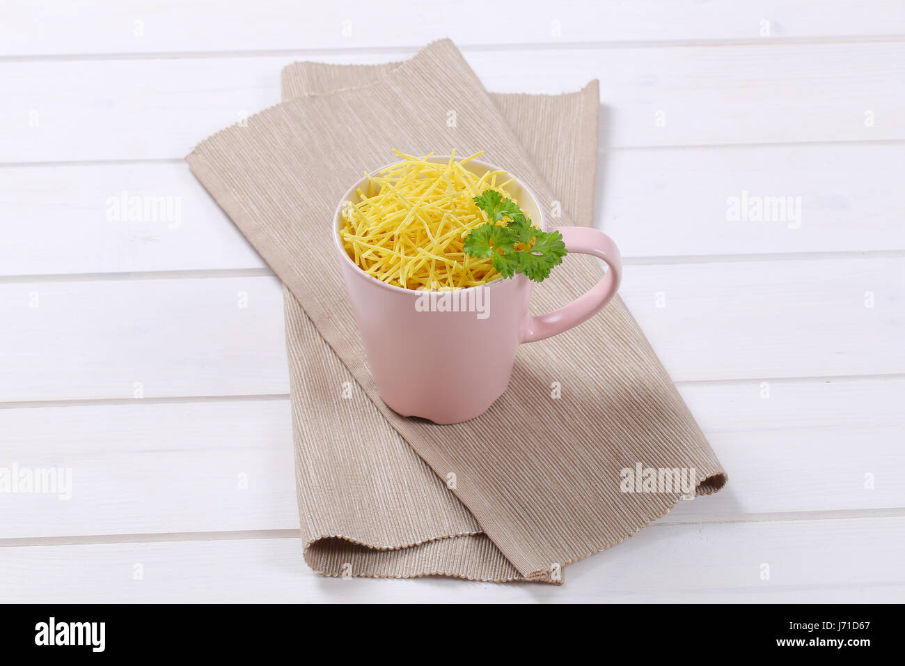 cup of dry soup noodles on beige place mat Stock Photo