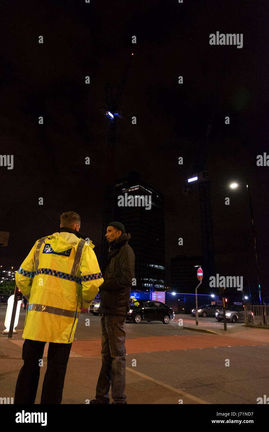 Manchester UK. Tuesday 23rd May 2017. A local taxi driver offers his services for free, to a police officer at the cordon on Angel Street. A number of taxi drivers have been offering their services to help stranded people get home. 22 people confirmed dead after explosion at an Ariana Grande concert at Manchester Arena.Copyright Credit: Ian Wray/Alamy Live News Stock Photo