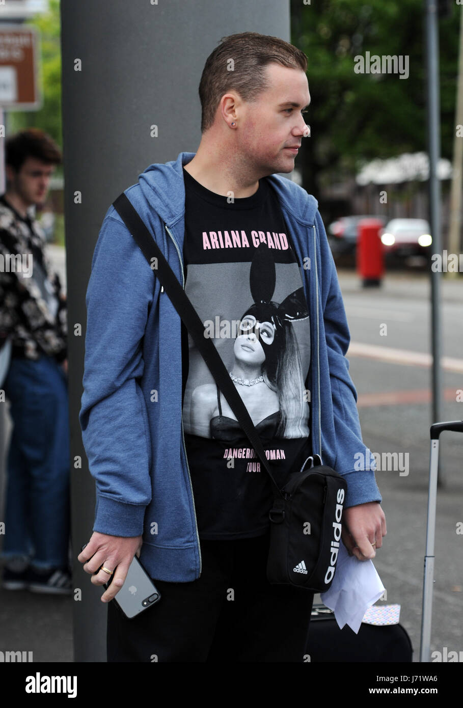 Manchester, UK. 23rd May, 2017. The scene outside the Manchester Arena, Manchester UK,  the morning after a suspected terrorist attack killed 22 people including children and injured 59 others at a concert by the pop star Ariana Grande. A concert goer waits to go home. Picture by Paul Heyes, Monday May 22, 2017. Credit: Paul Heyes/Alamy Live News Credit: Paul Heyes/Alamy Live News Stock Photo