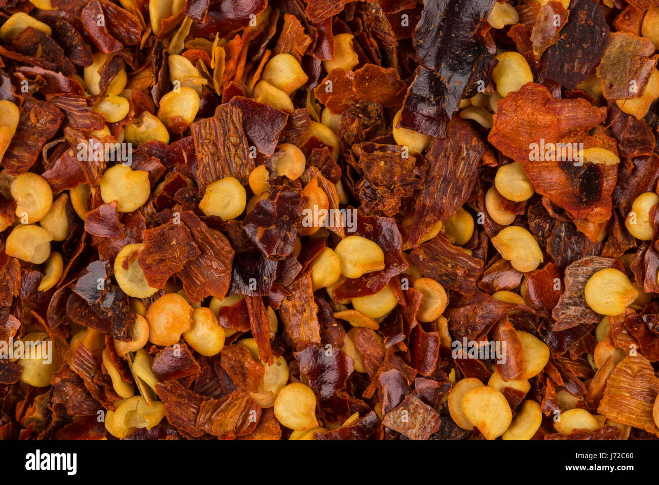 The pile of a crushed red pepper, dried chili flakes and seeds as a background Stock Photo Alamy