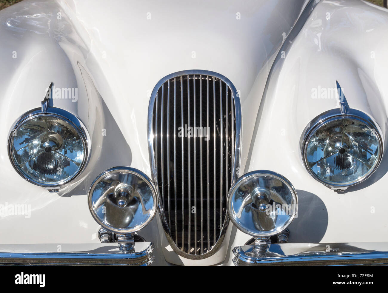 Close up of white vehicle hood and grill with chromed headlamps, spot lamps and bumpers Stock Photo