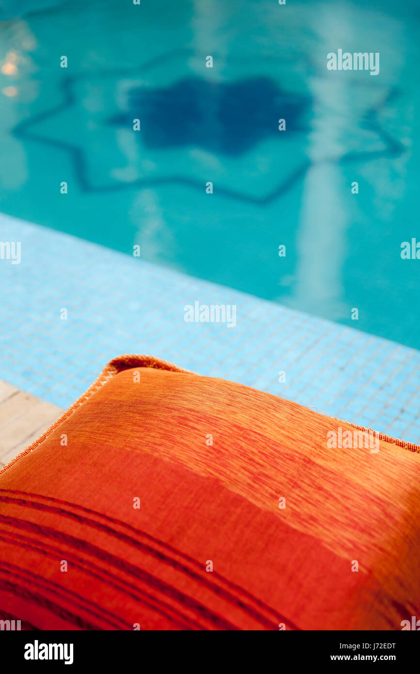 Blue swimming pool and red sitting cushion, Riad Africa, Marrakech, Morocco Stock Photo