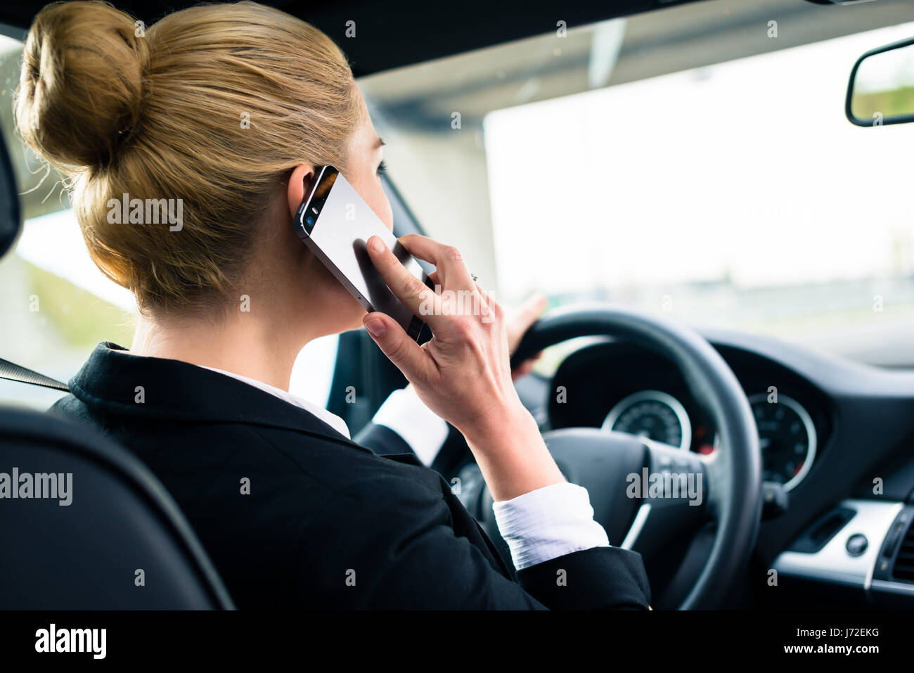 Woman using her phone while driving the car Stock Photo