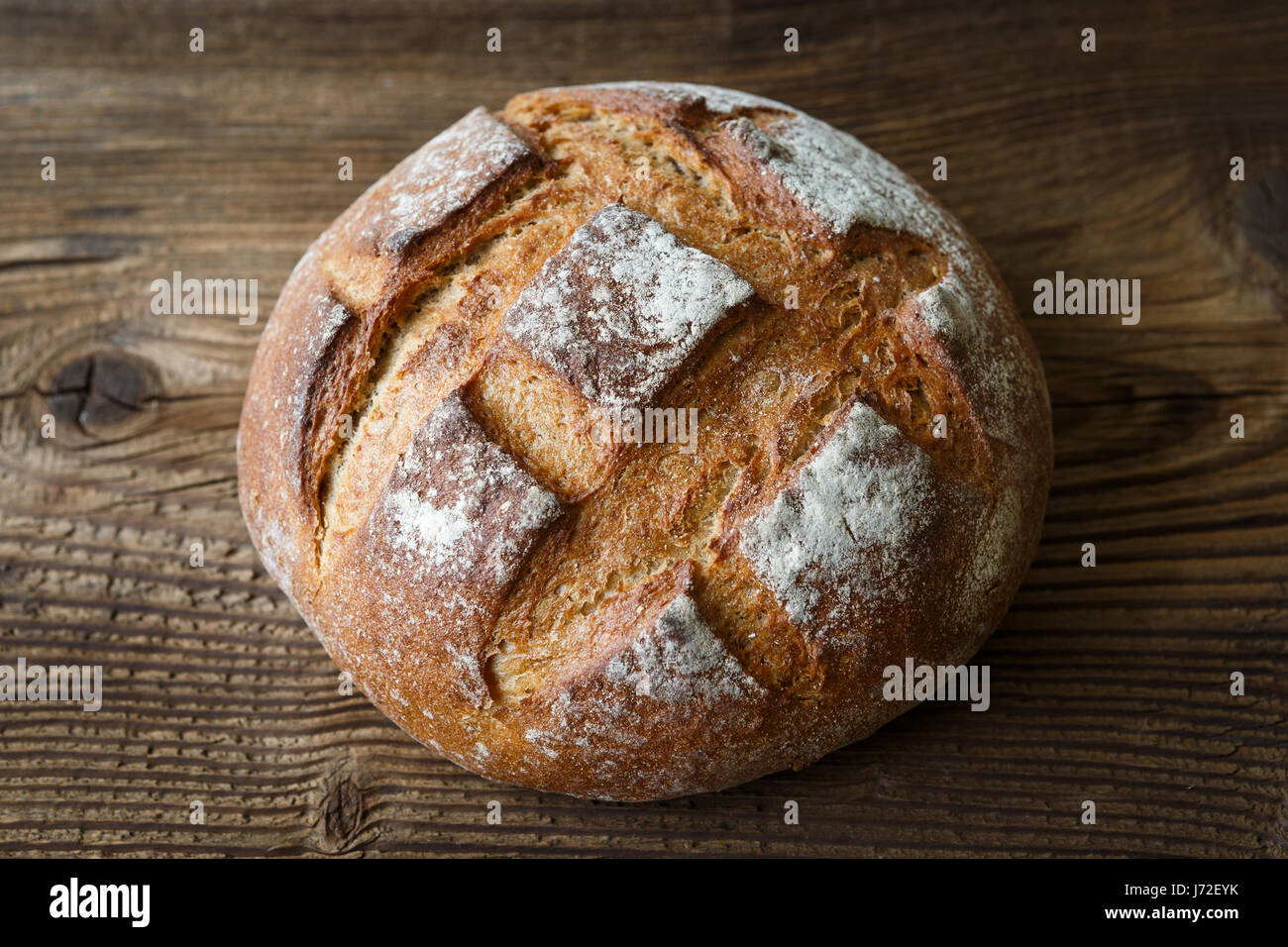 A freshly baked rustic, loaf of bread on an old wooden table Stock ...