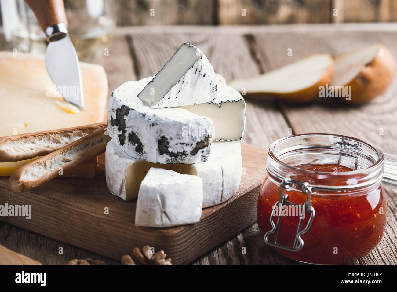 Cheese platter served with white wine, jam and walnuts on wooden board