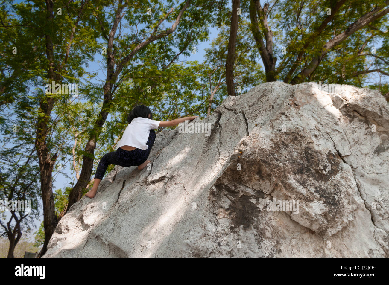 Young asian girl climbing rock boulder barehanded. Stock Photo