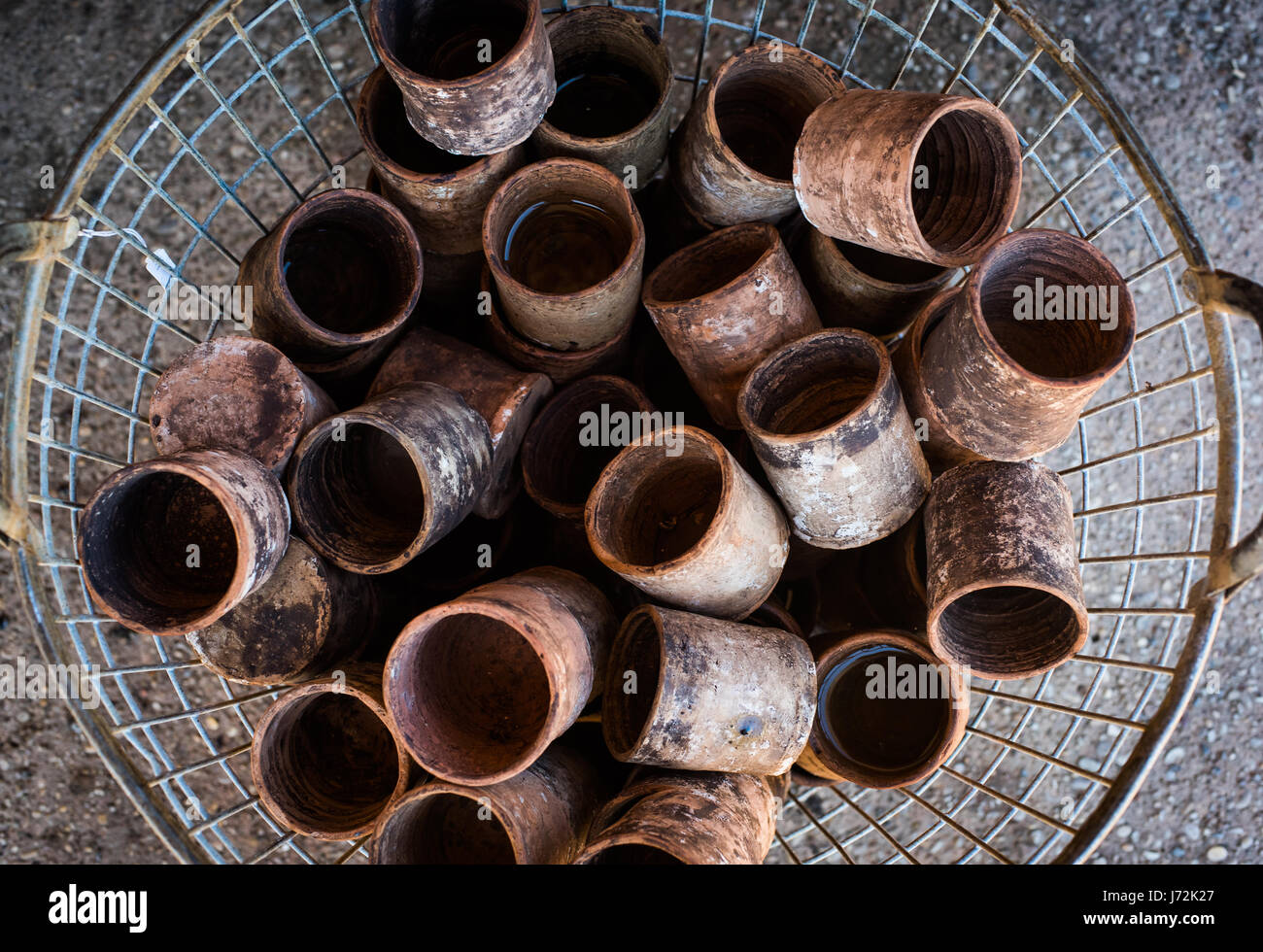 Basket with many clay glasses, old scratched crockery in antiques junk shop Stock Photo