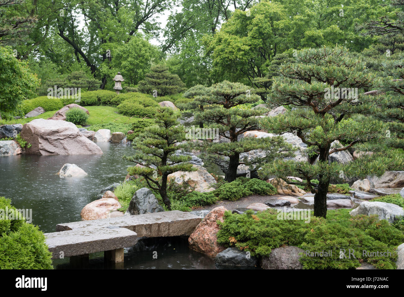 A stone bridge crosses a pond in a Japanaese garden Stock Photo