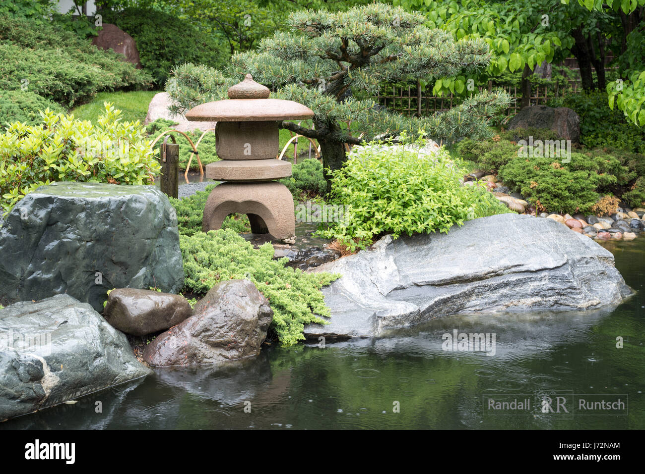 A stone lantern overlooks a pond in a Japanese garden Stock Photo