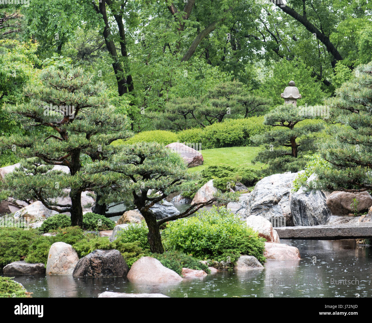 Stone lantern and pond in the rain a Japanese garden Stock Photo