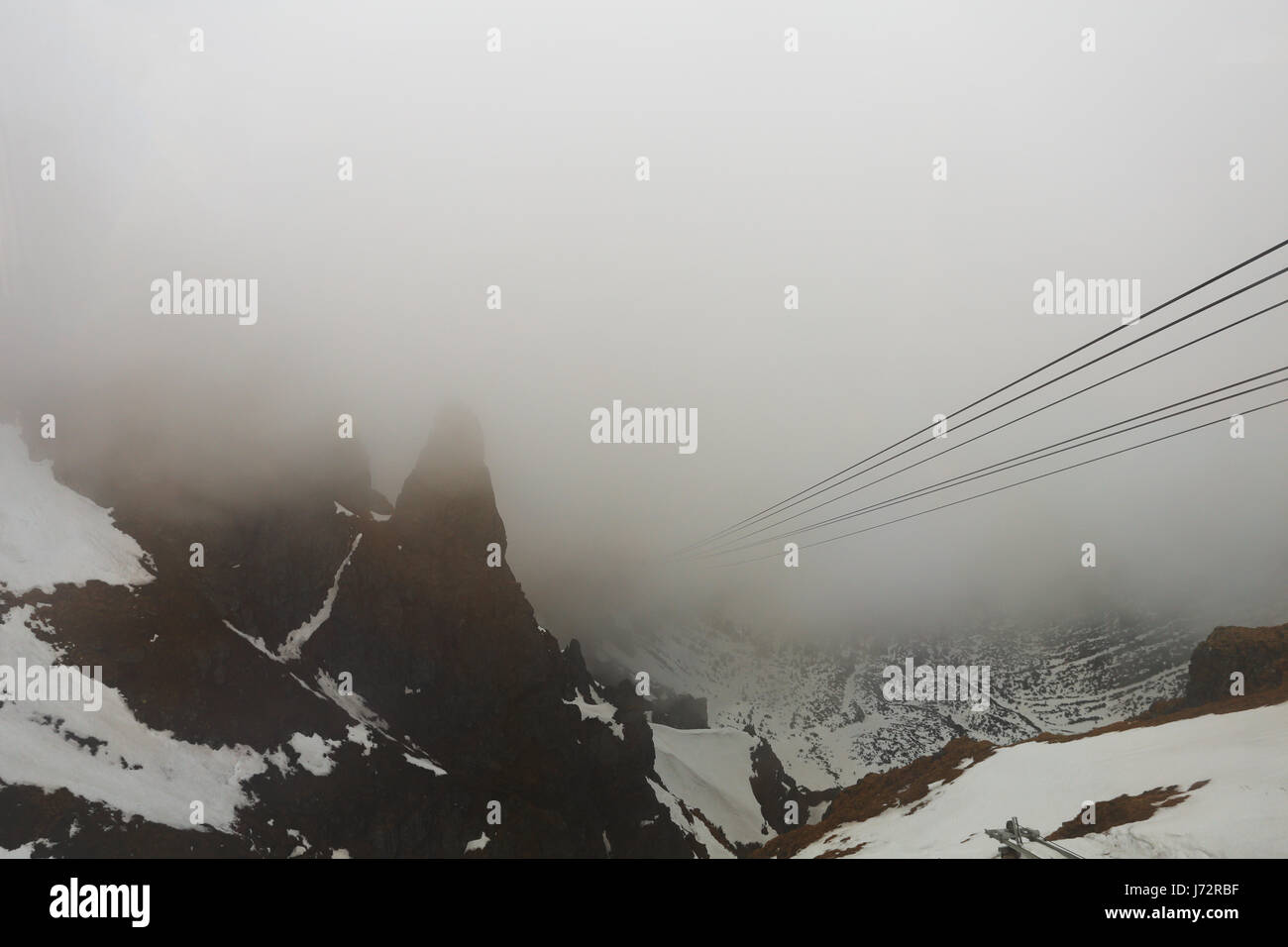 Dangerous downhill in fog. High cableway in fog. Foggy mountain landscape. Stock Photo