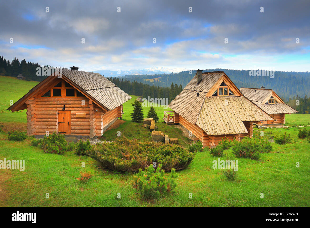 Ecological wooden houses on mounain hills. Wooden hotel on a sunny day. Beautiful place for rest. Morning landscape with green grass. Stock Photo