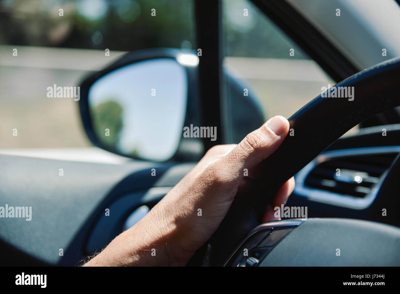 closeup of a young caucasian man driving a car in a road with several lanes Stock Photo