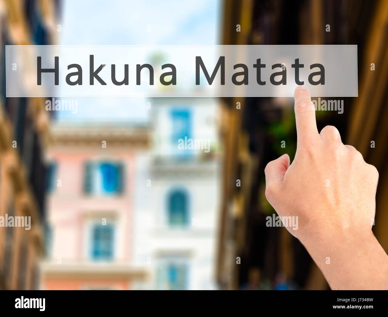 Hakuna Matata (Swahili phrase it means no worries) - Hand pressing a button on blurred background concept . Business, technology, internet concept. St Stock Photo