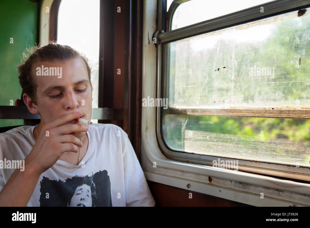 A person smoking a cigarette on a train in Cuba. Stock Photo