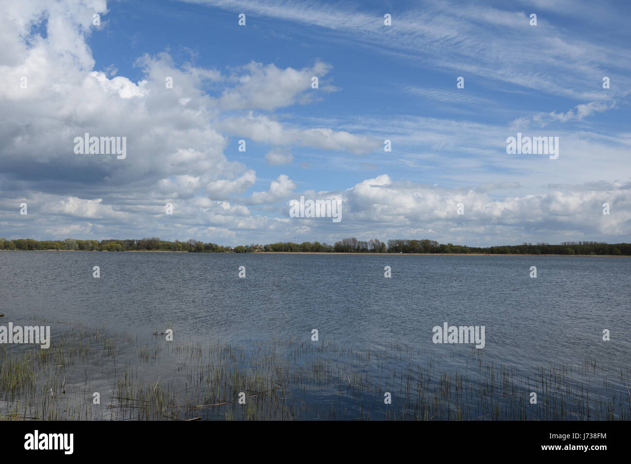 A scene of a lake and blue sky with fluffy white clouds Stock Photo - Alamy