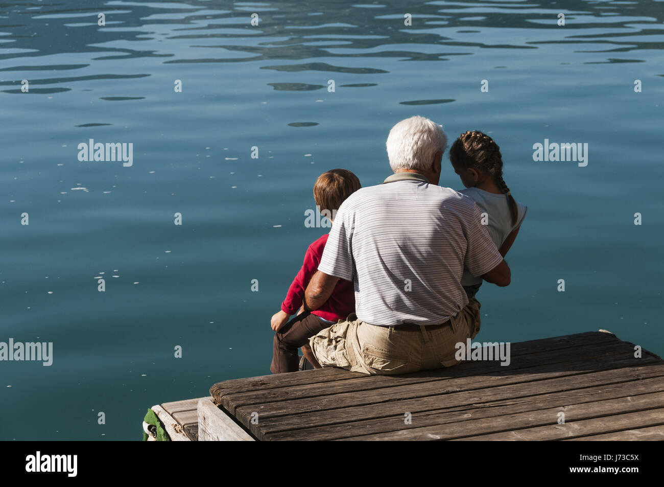 Man with grandchildren at Wolfsgangzee lake Stock Photo