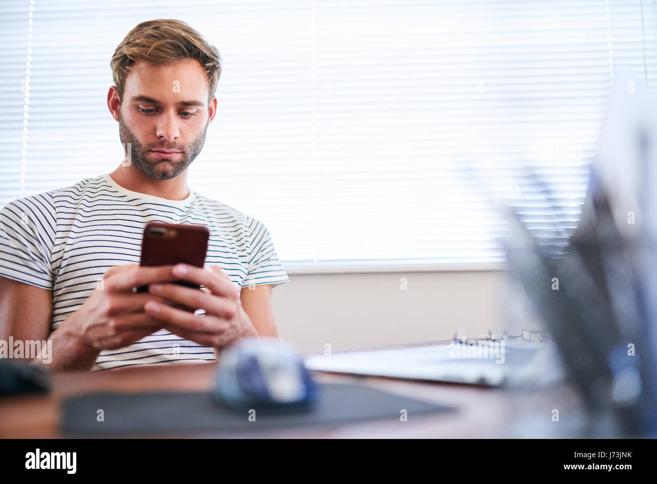 Adult caucasian man busy typing on his phone while seated Stock Photo